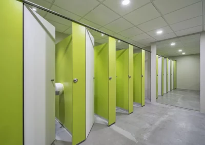 Cabinas de cuarto de baño con acabado en verde y puertas blancas en las oficinas de Endesa 2