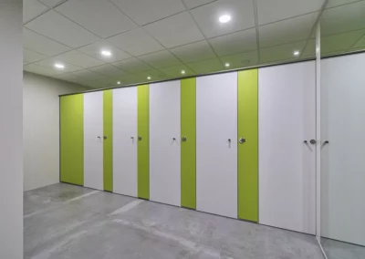 Cabinas de cuarto de baño con acabado en verde y puertas blancas en las oficinas de Endesa